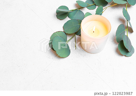 Burning aroma candle and green eucaliptus leaves Burning aroma candle and green eucaliptus leaves 122023987