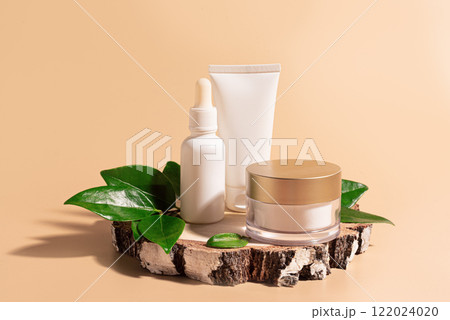 Beauty products packaging with green leaves on wooden cut 122024020