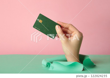 Female holding a credit card Visa break through the paper on pink background. Nikolaev, Ukraine - February 14, 2022 122024235