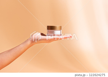 Woman hand hold cosmetic cream jar 122024275