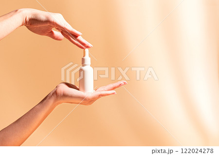 Woman hands hold white serum bottle 122024278