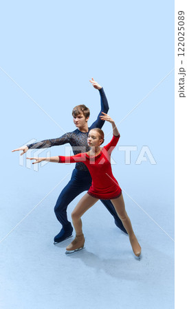 Dynamic movement. Figure skating duo captivates audience with their graceful moves on ice against cold blue background. 122025089