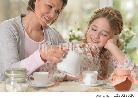 Happy mom and daughter drinking tea at home 122025620