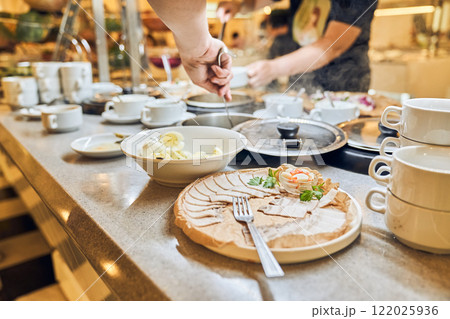 A person selects and serves breakfast dishes in the hotel restaurant. Buffet for a hearty lunch with space for copying. High quality photo A person selects and serves breakfast dishes in the hotel restaurant. Buffet for a hearty lunch with space for copying. High quality photo 122025936