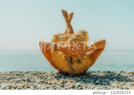 Beach Relaxation woman lies on a pebble beach, legs raised, and arms spread out. The concept of travel, vacation at sea Beach Relaxation woman lies on a pebble beach, legs raised, and arms spread out. The concept of travel, vacation at sea 122026153
