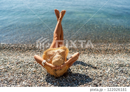 Beach Relaxation woman lies on a pebble beach, legs raised, and arms spread out. The concept of travel, vacation at sea Beach Relaxation woman lies on a pebble beach, legs raised, and arms spread out. The concept of travel, vacation at sea 122026181