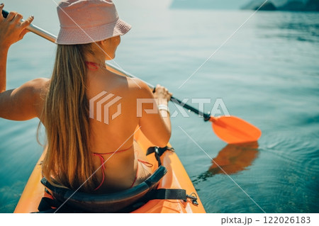 Woman in kayak back view. Happy woman with long hair in a swimsuit and hat floating in kayak on the sea. Summer holiday vacation. Summer holidays vacation at sea. Woman in kayak back view. Happy woman with long hair in a swimsuit and hat floating in kayak on the sea. Summer holiday vacation. Summer holidays vacation at sea. 122026183