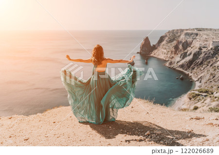 Woman green dress sea. Female dancer posing on a rocky outcrop high above the sea. Girl on the nature on blue sky background. Fashion photo. Woman green dress sea. Female dancer posing on a rocky outcrop high above the sea. Girl on the nature on blue sky background. Fashion photo. 122026689