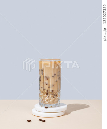 Iced coffee latte in a tall glass with milk on a yellow and blue background 122027329