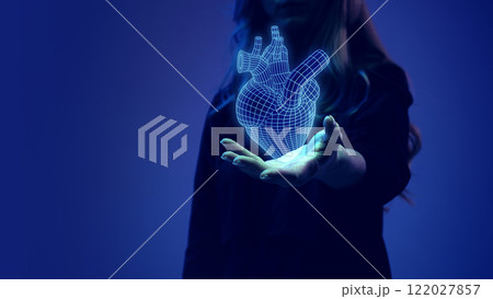Female hand presenting a glowing digital heart hologram, representing medical innovation and cardiovascular research. Female hand presenting a glowing digital heart hologram, representing medical innovation and cardiovascular research. 122027857