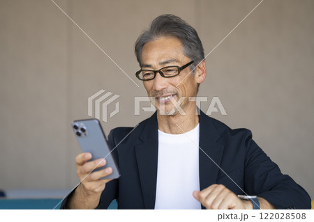 スマートフォンの画面を見るメガネをかけた60代の男性 122028508