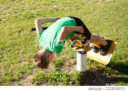Boy upside down on playground equipment enjoying a sunny day outdoors. Boy upside down on playground equipment enjoying a sunny day outdoors. 122029251