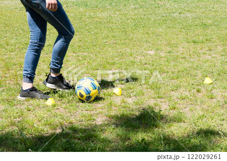 Soccer practice: A young person practicing their skills with a ball and cones on a grassy field. 122029261