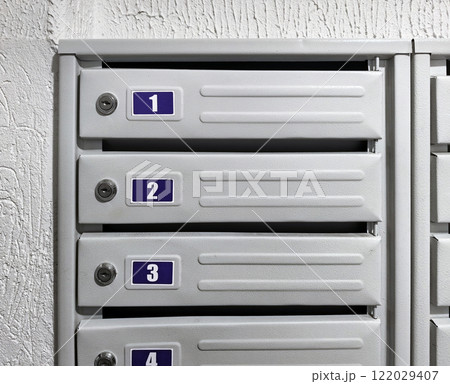 A row of gray mailboxes on a white background. Numbering of boxes in the entrance of an apartment building. Delivery of correspondence, magazines, letters, newspapers and postcards by mail 122029407