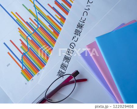 テーブルに置かれたグラフとメガネと書類と手帳 122029408