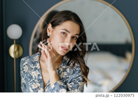 Woman wearing pajamas posing in elegant bedroom with blue walls 122030975