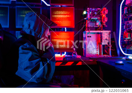 Back view of female hacker breaks into data center, Blockchain cyber attack, Woman hacker wear hood sit front computer typing on keyboard hacking servers, Gamer woman streaming game online dark room 122031065