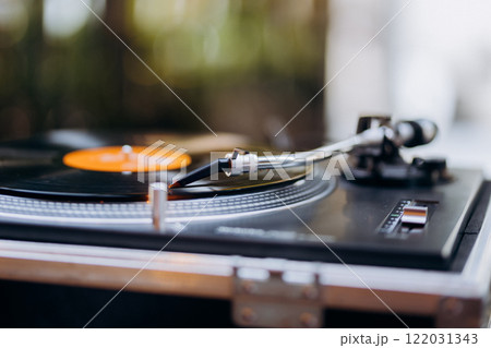 Turntable needle on a spinning vinyl record, evoking vintage charm and timeless music vibes Turntable needle on a spinning vinyl record, evoking vintage charm and timeless music vibes 122031343