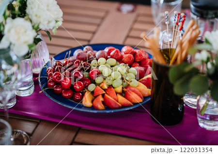 Fresh fruit platter with strawberries, grapes, and peaches on table, perfect for summer events Fresh fruit platter with strawberries, grapes, and peaches on table, perfect for summer events 122031354