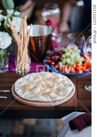 Delicious flatbread served alongside fresh fruit and breadsticks on a beautifully set dining table 122031358