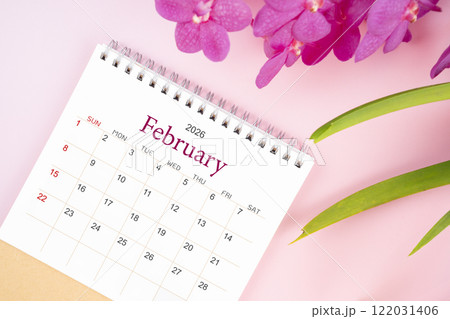 Desk calendar for February 2026 with blooming pink orchid. Flay lay. 122031406