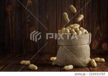 unshelled peanuts falling in sack on table 122031787