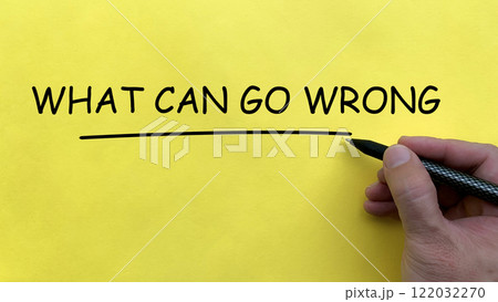Hand writing What Can Go Wrong text on yellow cover board. 122032270