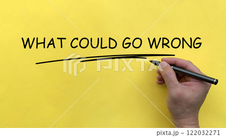Hand writing What Could Go Wrong text on yellow cover board. 122032271