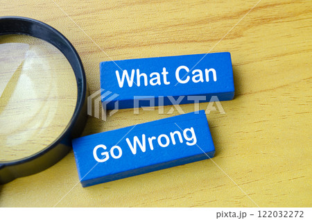 Top view of What Can Go Wrong text on blue wooden blocks with magnifying glass. 122032272
