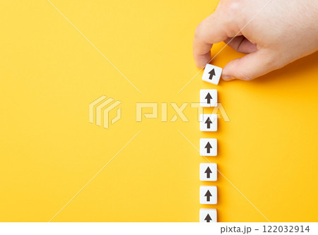 Hand making a row of arrows on a yellow background. Space for text. Paving the way, making plans. Next steps and vision. Course to go forward. Hand making a row of arrows on a yellow background. Space for text. Paving the way, making plans. Next steps and vision. Course to go forward. 122032914