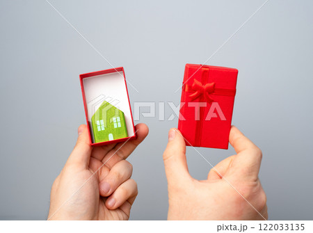 A house figurine in an open gift box. Give a home and start a life together. Buy your grown-up children their own home. A gift for Valentine's Day. Mortgage. A house figurine in an open gift box. Give a home and start a life together. Buy your grown-up children their own home. A gift for Valentine's Day. Mortgage. 122033135