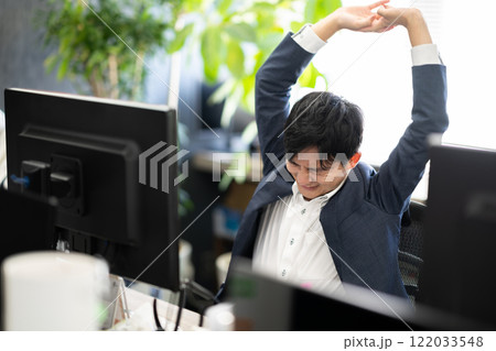 オフィスワーク　イメージ　パソコンの前でストレッチをする男性 122033548