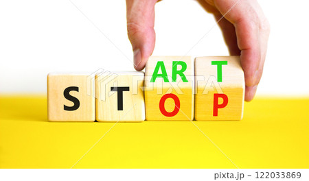 Start or stop symbol. Concept words Start or Stop on beautiful wooden block. Beautiful yellow table white background. Businessman hand. Business start or stop concept. Copy space. Start or stop symbol. Concept words Start or Stop on beautiful wooden block. Beautiful yellow table white background. Businessman hand. Business start or stop concept. Copy space. 122033869