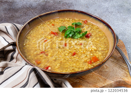 Hearty lentil soup with tomatoes and herbs served in a bowl on a wooden surface, perfect for a cozy meal at home 122034536