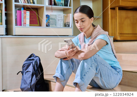 Teenage female student using smartphone, inside high school library Teenage female student using smartphone, inside high school library 122034924