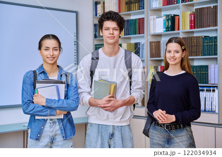 Group of college students teenage girls and guy looking at camera inside library classroom Group of college students teenage girls and guy looking at camera inside library classroom 122034934
