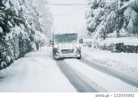 Delivery van on a snow covered winter road during snowstorm Delivery van on a snow covered winter road during snowstorm 122035082