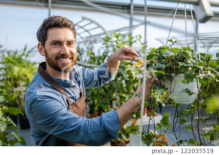 Young bearded man working with plants in a greenhouse 122035519