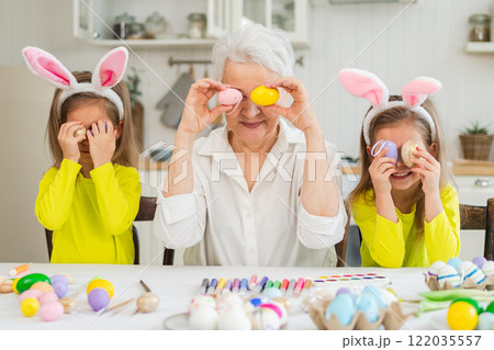 Happy Easter. Two little girls sisters twins grandmother painting eggs enjoying time together. Happy family grandma granddaughters child kids preparing for Easter. Spring Christian festival tradition Happy Easter. Two little girls sisters twins grandmother painting eggs enjoying time together. Happy family grandma granddaughters child kids preparing for Easter. Spring Christian festival tradition 122035557