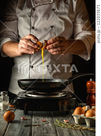 A talented chef demonstrates culinary expertise by cracking fresh eggs into a sizzling frying pan A talented chef demonstrates culinary expertise by cracking fresh eggs into a sizzling frying pan 122035671