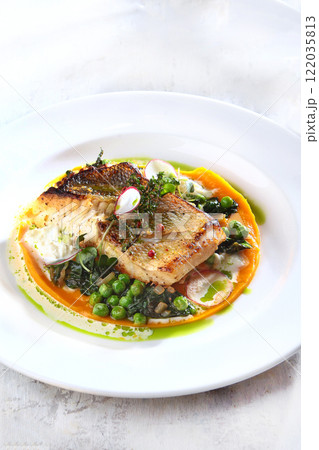 Dorado fish fillet baked with vegetables on white plate. Festive dishes for banquet. White fish. Festive dish of white fish. White background. 122035813