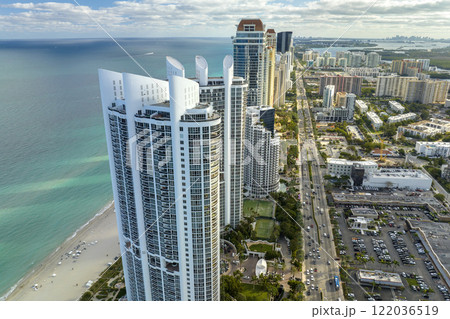 View from above of luxurious highrise hotels and condos on Atlantic ocean shore in Sunny Isles Beach city. Urban street with busy traffic. American tourism infrastructure in southern Florida 122036519
