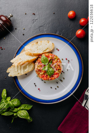 Guacamole tartare with fresh vegetables, basil garnish, and crispy baguette slices on a white plate Guacamole tartare with fresh vegetables, basil garnish, and crispy baguette slices on a white plate 122036618