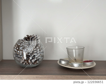 Glass bowl filled with frosted pinecones as a decorative accent. Clean minimalistic design reflects winter aesthetics and holiday warmth 122036651