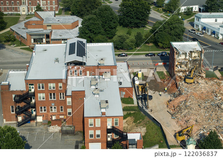 Old building demolition site. Construction excavator tearing down obsolete brick walls. City planning concept 122036837