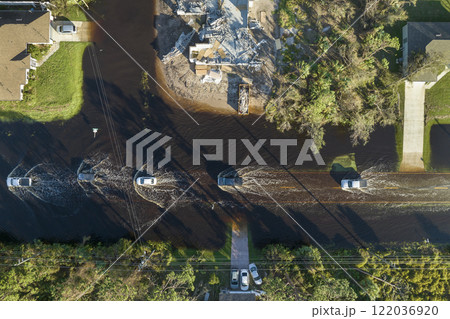 Flooded american street with moving vehicles and surrounded with water houses in Florida residential area. Consequences of hurricane natural disaster Flooded american street with moving vehicles and surrounded with water houses in Florida residential area. Consequences of hurricane natural disaster 122036920
