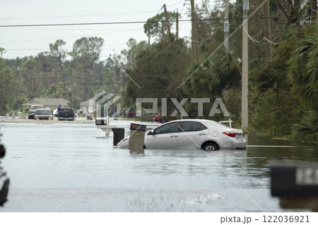 Flooded American street with stuck vehicle surrounded with water in Florida residential area. Consequences of hurricane natural disaster Flooded American street with stuck vehicle surrounded with water in Florida residential area. Consequences of hurricane natural disaster 122036921
