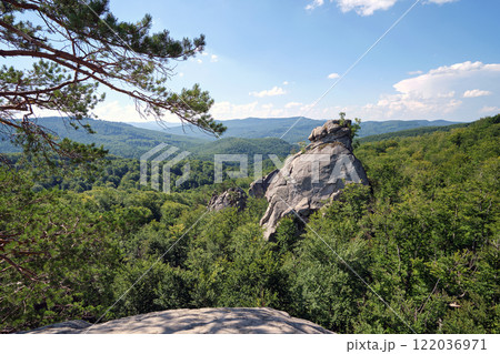 Huge rocky boulder formations high in mountains with growing trees on summer sunny day 122036971