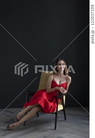 portrait of a beautiful young woman in a red dress, studio shot on a dark background portrait of a beautiful young woman in a red dress, studio shot on a dark background 122037189