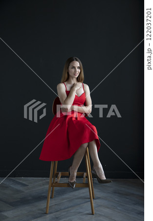 portrait of a beautiful young woman in a red dress, studio shot on a dark background 122037201